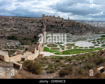 Ampia vista panoramica delle mura dell'Alcazaba de Almería con giardini terrazzati e paesaggio urbano di Almería sotto un cielo coperto in Andalusia, Spagna. Foto Stock