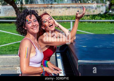 Donne diverse che celebrano l'orgoglio suonando il pianoforte all'aperto Foto Stock