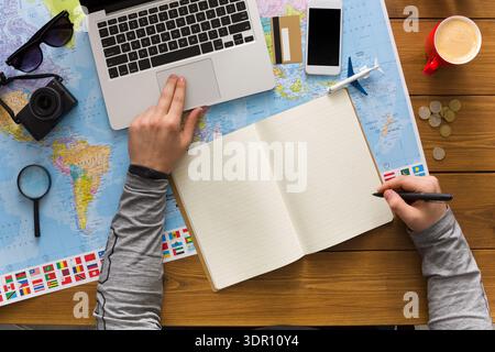 Sessione di pianificazione del viaggio con laptop e mappa su un tavolo di legno Foto Stock
