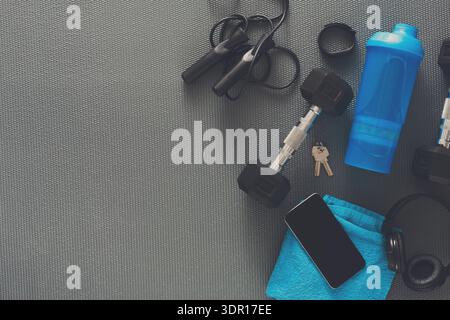 Disposizione delle attrezzature per l'allenamento su superficie grigia con accessori e bottiglia d'acqua visibili Foto Stock