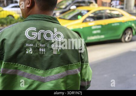 Bangkok, Thailandia. 25 marzo 2025. Guida, mangia, consegna, logo del servizio di consegna del cibo Grab visualizzato sulla camicia di un corriere Grab a Bangkok Foto Stock