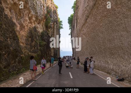 Pecatu, Uluwatu, Bali, Indonesia - 15 febbraio 2025: Turisti che passeggiano attraverso la splendida strada scolpita dalla scogliera fino a Pandawa Beach, con una limosità assoluta Foto Stock
