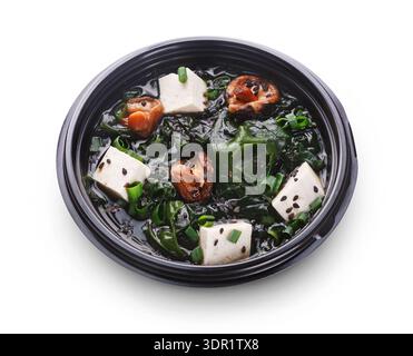 Zuppa di verdure con tofu e frutti di mare in una ciotola nera su sfondo bianco Foto Stock