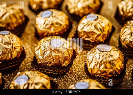 Cioccolatini Ferrero Rocher premium su sfondo glitter dorato Foto Stock