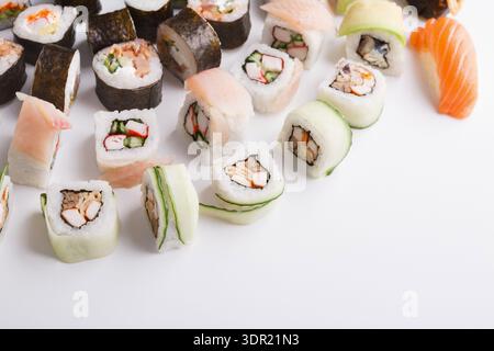 Collezione di sushi Rolls disposti su una superficie bianca con vari ripieni e condimenti esposti Foto Stock