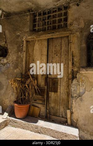 Una doppia porta in legno intemprata in un edificio abbandonato a Monreale, in Sicilia. Architettura vernacolare tra la fine del XIX e l'inizio del XX secolo. Legno non verniciato Foto Stock