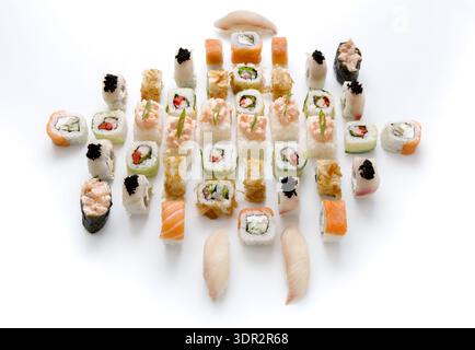 Vari tipi di sushi disposti ordinatamente su un piatto bianco per cena Foto Stock