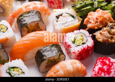 Collage di sushi che mostra vari tipi di rotoli di sushi e frutti di mare su una superficie bianca Foto Stock