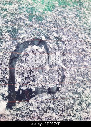 Una semplice forma di cuore disegnata a mano in uno strato di neve bianca fresca su una superficie di vetro. Un romantico e tranquillo dettaglio invernale catturato in Ungheria Foto Stock
