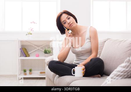 Raccolta di momenti in un accogliente salotto con una donna che si gode un drink Foto Stock