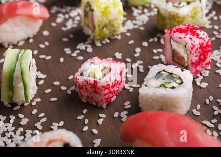 Varietà di pezzi di sushi disposti su una superficie di legno con riso sparso intorno Foto Stock