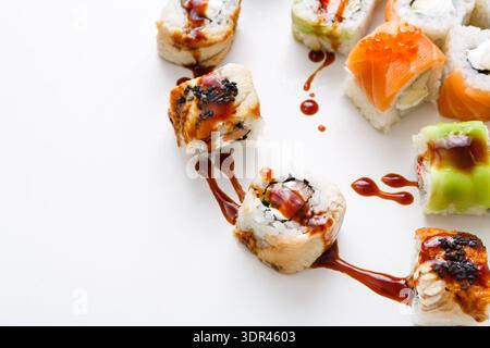 Deliziosi sushi Rolls serviti su un piatto bianco con salsa trapanata sulla parte superiore Foto Stock