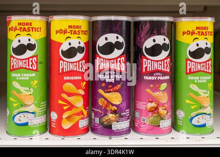 Penang, Malesia - 16 aprile 2025: Vari sapori di PRINGLES sono disposti su uno scaffale, tra cui Sour Cream & Onion, Original, Spicy Texas Style BBQ, Foto Stock