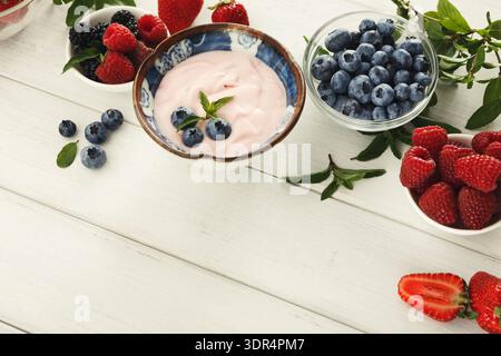 Raccolta di bacche e yogurt su un tavolo di legno bianco per spuntini e dessert salutari Foto Stock