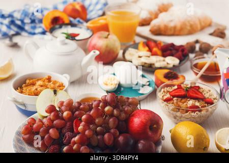 Collezione di prodotti per la colazione su un tavolo in un ambiente accogliente con frutta e pasticcini Foto Stock