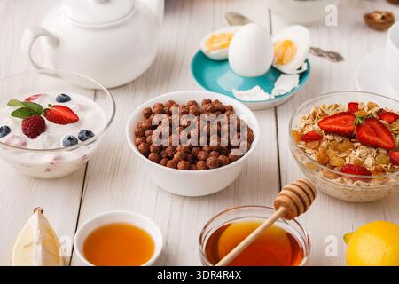 Deliziosa colazione a buffet con frutta, cereali e bevande preparate su un tavolo di legno Foto Stock