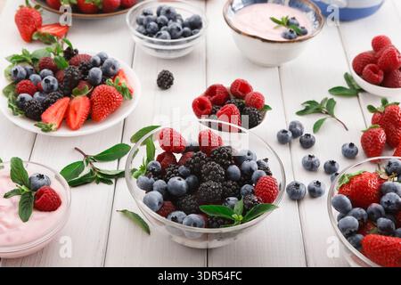 Raccolta di frutta fresca e yogurt su un tavolo di legno con ciotole e frutti di bosco Foto Stock