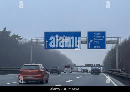 Autobahn A2 bei Lehrte, Deutschland, Europa. Mehrspurige Fahrbahn mit moderatem Verkehr, Pkw und Transporter, aufgenommen aus einem fahrenden Fahrzeug. Große blaue Überkopfwegweiser zeigen Richtung Dortmund und Hannover mit Hinweis Messe sowie Kassel, Hamburg und Brema über die A7 in 500 m. Neblige Winterbedingungen mit eingeschränkter Sicht, bewaldete Randbereiche und Brückenbauwerke im Hintergrund. *** Autostrada A2 nei pressi di Lehrte, Germania, Europa strada a più corsie con traffico moderato, automobili e furgoni, preso da un veicolo in movimento grandi cartelli blu in testa che puntano verso Dortmund e Hannover wi Foto Stock