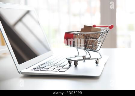 Concetto di shopping su Internet. Carrello sulla tastiera del computer portatile Foto Stock