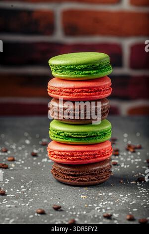 Macaron colorati si impilano sul tavolo scuro Foto Stock