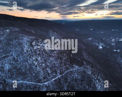 Vista aerea in dondolo di un sentiero innevato che si snoda lungo la dorsale di Shawangunk al tramonto in inverno, Hudson Valley, New York, Stati Uniti. Foto Stock