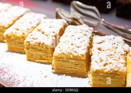 Torta a strati con panna, torta Napoleone. Fette di millefoglie con zucchero a velo. Gustoso cibo dolce. Delizioso dessert. Foto Stock