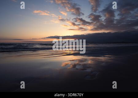 Tramonto sull'Oceano Pacifico con riflessi sulla sabbia bagnata, sull'isola Isabela e sulle isole Galapagos. Foto Stock