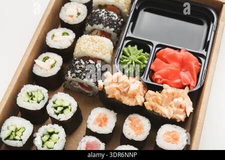 Sushi Rolls e contorni posti in una scatola da asporto per un pasto o uno spuntino in un ambiente semplice Foto Stock