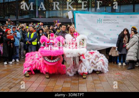 Il nuovo anno lunare 2026 celebra a Time Square di Warrington per dare il benvenuto all'anno del cavallo. I Warrington Hongkongers mettono in scena uno spettacolo con la danza del drago, bancarelle tradizionali che offrono arte e artigianato, giocattoli e regali cinesi e cibo di strada. I classici giochi di carnevale di Hong Kong erano disponibili insieme a esperienze culturali come fai Chun, la calligrafia cinese e il racconto della fortuna. Sarah Hall si pone con il leader dei Warrington Hongkongers dietro draghi rosa e bianco. Crediti: John Hopkins/Alamy Live News Foto Stock