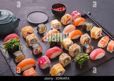 Collezione di sushi Rolls su un piatto di pietra nera con tè e zenzero martellato Foto Stock