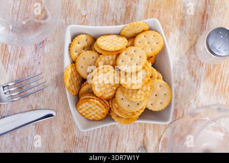 Cracker croccanti a forma di disco leggermente salati in piatto sul tavolo Foto Stock