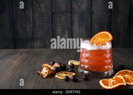 Bevanda all'arancia con frutta secca e frutti di bosco su un tavolo di legno in un ambiente accogliente Foto Stock