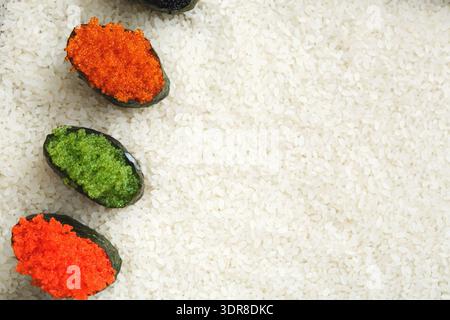 Sushi Rolls con guarnizioni colorate collocate su un letto di riso bianco su una superficie di legno Foto Stock