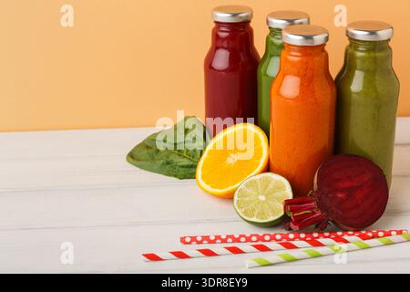 Varietà di succhi freschi con frutta e verdura esposte su un tavolo di legno bianco Foto Stock