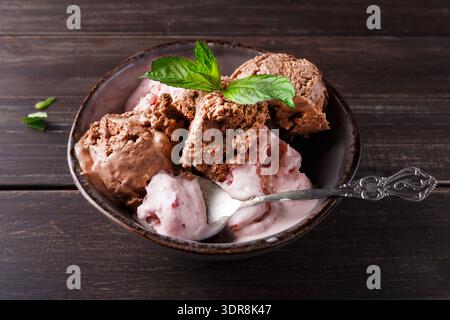 Ciotola di gelato con cioccolato e fragole su un tavolo di legno Foto Stock