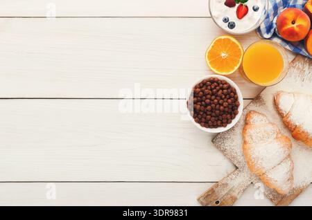 Colazione a buffet con frutta fresca, pasticcini e bevande disposte su un tavolo di legno Foto Stock