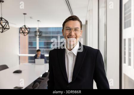 Un uomo d'affari sicuro in abito nero in piedi nella moderna sala riunioni Foto Stock
