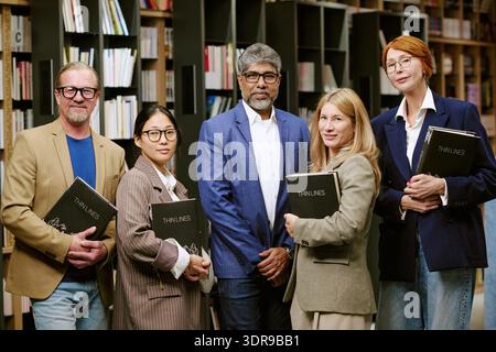 Gruppo diversificato di uomini e donne che tiene libri in posa con autore alla presentazione Foto Stock