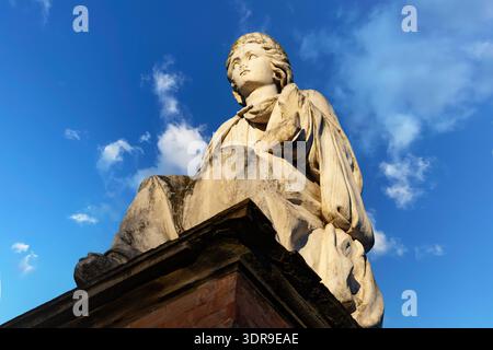 Scultura classica illuminata dal sole di una giovane figura allegorica femminile nell'Italia settentrionale, caratterizzata da delicati tratti facciali e da abiti drappeggiati che scorrono Foto Stock