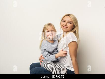 Madre e figlia condividono un momento seduti insieme in un ambiente semplice Foto Stock