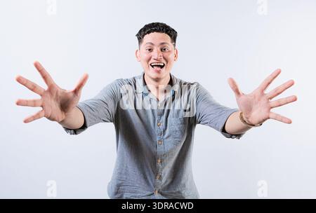 Felice giovane latino che accoglie a braccia aperte isolato. Persone ospitali che aprono le braccia alla telecamera. Uomo sorridente che chiede un Foto Stock