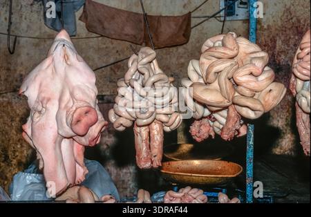 Eingescanntes Diorgov einer historischen Farbaufnahme eines ausgenommenen Schweins mit Innereien und Gedärmen in einer Markthalle a Saigon, Vietna Foto Stock
