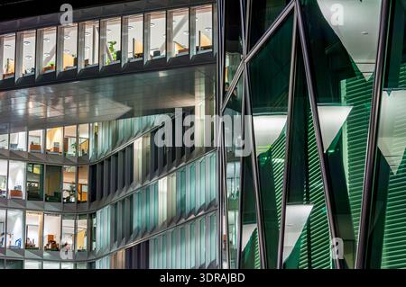 Uffici open space e piani di un moderno edificio per uffici la sera con illuminazione artificiale Foto Stock