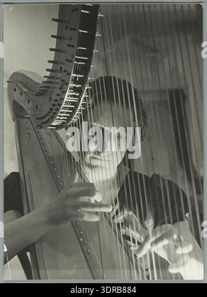Una fotografia del 1934 mostra un arpista che esegue musica, concentrandosi sulle singole prestazioni dell'arpa. L'immagine documenta la tecnica musicale, l'uso degli strumenti e la pratica esecutiva dei primi anni del XX secolo. Illustra l'apprezzamento culturale della musica dell'arpa, l'ambientazione del palcoscenico o dello studio e il ruolo dei musicisti nell'espressione artistica durante questo periodo. Foto Stock
