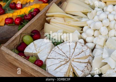 Vassoio di formaggi con formaggi assortiti, ciliegie e uva Foto Stock