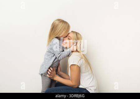 Madre e figlia condividono un momento in una camera semplice durante un pomeriggio tranquillo Foto Stock