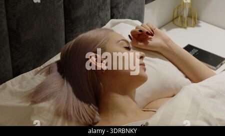Giovane donna bionda che dorme a letto durante la notte Foto Stock