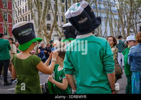 17 marzo 2024 - Lisbona, Portogallo: Partecipanti in abiti verdi e cappelli divertenti che partecipano alla sfilata festosa di bagpiper nella giornata di sole. La folla si riunisce nel viale centrale per celebrare il giorno di San Patrizio. Attività familiari, atmosfera culturale, patrimonio irlandese Foto Stock
