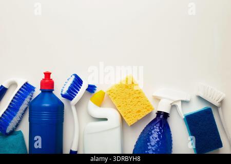 Raccolta di materiali di consumo per la pulizia disposti in un modello ordinato su uno sfondo semplice Foto Stock