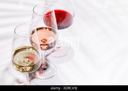 Tre bicchieri da vino pieni di vino rosso, bianco e rosa Foto Stock